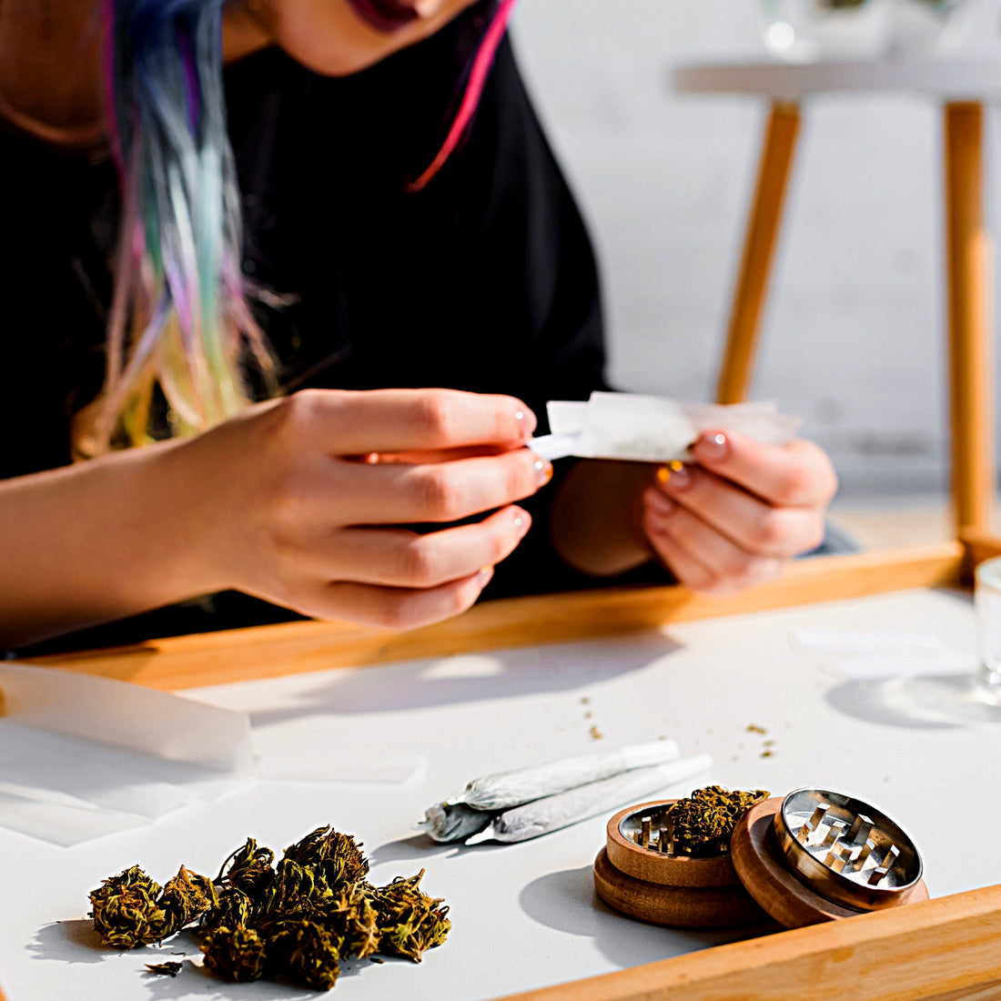 Herb grinder and herbs with girl rolling joint background