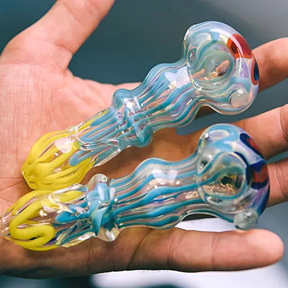 Close up view hand holding 2 glass spoon pipes